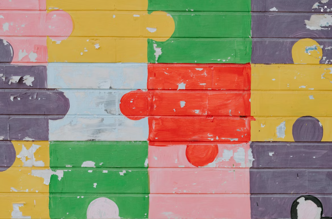 Colourful jig-saw pieces painted on a brick wall.